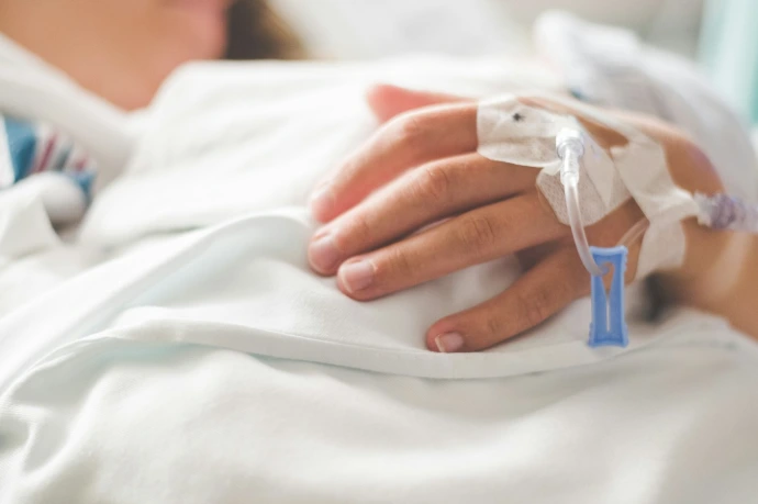 a woman laying in a hospital bed with an iv in her hand